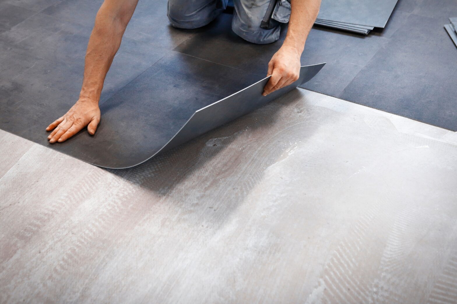 A worker installing vinyl flooring tiles